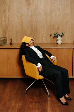 Exhausted businesswoman resting with book covering face, burnout