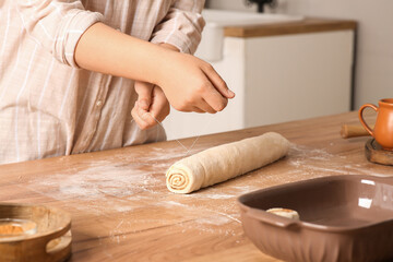 Woman preparing traditional cinnamon rolls in kitchen