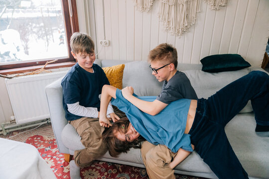 Siblings engaged in playful wrestling on a cozy sofa
