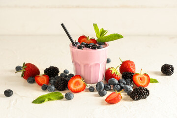 Glass of fresh smoothie with different berries and mint on white wooden background