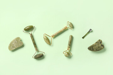 Different facial massage tools on green background