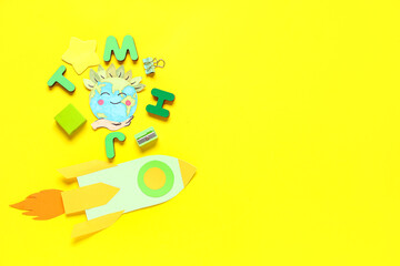 School stationery, paper rocket and planet Earth on yellow background