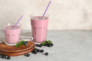 Glasses of fresh blueberry smoothie with mint and berries on white background