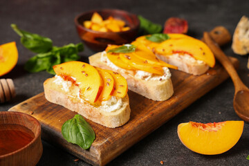 Wooden board of peach bruschetta with ricotta, flax seeds and basil on black background, closeup