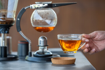 A man is pouring tea into a cup from a glass pitcher