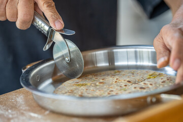A person is cutting a tortilla with a pizza cutter