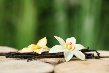 Aromatic vanilla pods and flowers on table outdoors