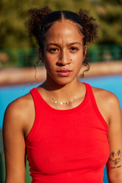 Young female looking at camera while standing against blurred ba