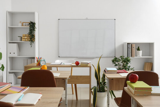 Interior of empty classroom with school desks and clean whiteboard