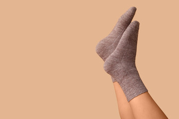 Legs of young woman in grey cotton socks on brown background