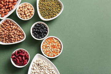 Composition with bowls of different legumes on green background