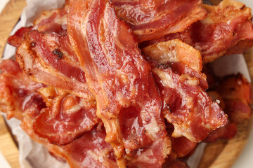 Wooden plate with fried bacon rashers on white background, closeup