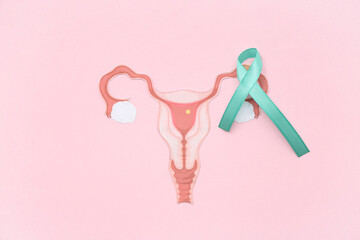 Turquoise ribbon with paper uterus on pink background. Cervical Health Awareness Month