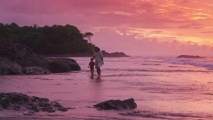 A devoted father and his young son stroll hand in hand on the sandy beaches of Costa Rica at sunset, captivated by the skies and waves, creating unforgettable memories theyll cherish forever - Powered by Adobe