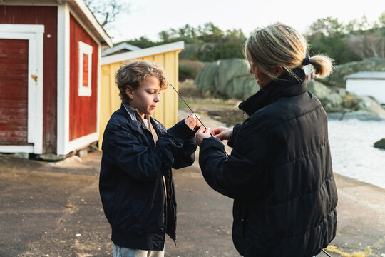 Mother and Son Adjusting Fishing Rod Together on a Pier 