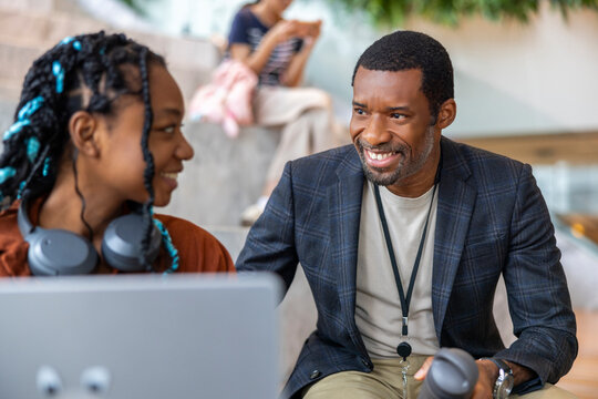Smiling father looking at daughter using laptop with pride
