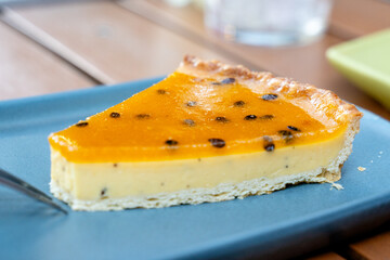 Slice of Passion Fruit Tart with Golden Glaze on Blue Plate