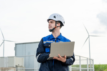 Caucasian male technician working outdoors in the wind turbines field. 