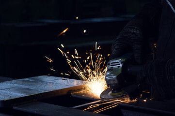 A person using an angle grinder on a metal surface with bright sparks.