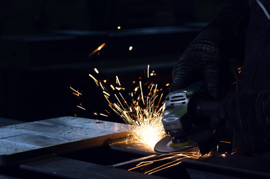 A person using an angle grinder on a metal surface with bright sparks.