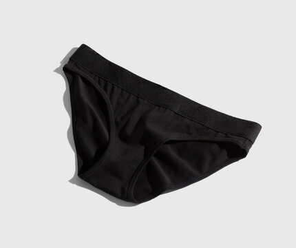 A pair of black brief style underwear on light grey background.