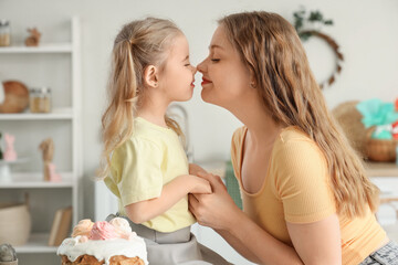 Happy mother and her cute daughter with freshly baked Easter cake in kitchen