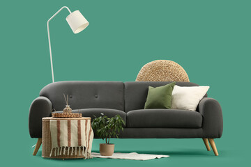 Stylish grey sofa, coffee table and standard lamp on green background