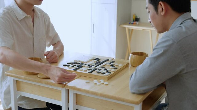 Asian young men playing board game Go during competition in community. 