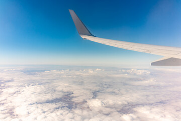 View from the airplane window at a beautiful cloudy sky and the airplane wing