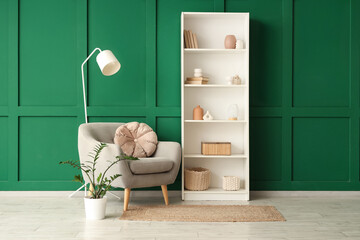 Armchair, shelving unit and lamp near green wall in room