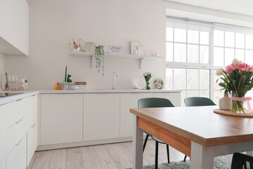 Interior of light kitchen decorated for Easter with dining table, shelf and counters