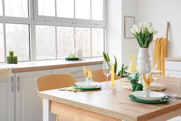 Dining table set for Easter with tulips in light kitchen