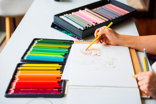 Artist Drawing with Rainbow Colored Pencil Collection on White D