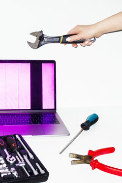 Person holding tools and trying to fix and repair a broken laptop 