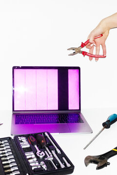 Person holding tools and trying to fix and repair a broken laptop 