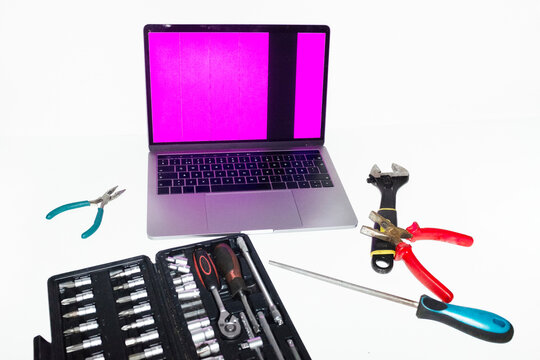 Person holding tools and trying to fix and repair a broken laptop 