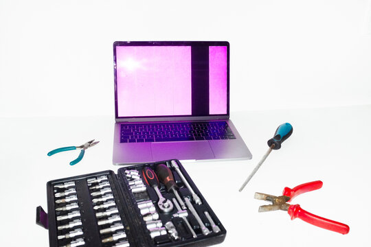 Person holding tools and trying to fix and repair a broken laptop 