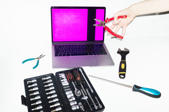 Person holding tools and trying to fix and repair a broken laptop 