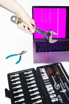 Person holding tools and trying to fix and repair a broken laptop 