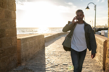 Traveler walking seaside during phone call