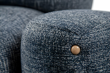 Close-up detail of textured fabric on modern furniture, showcasing a subtle button detail.  Ideal for interior design, home d&eacute;cor, and textile websites.