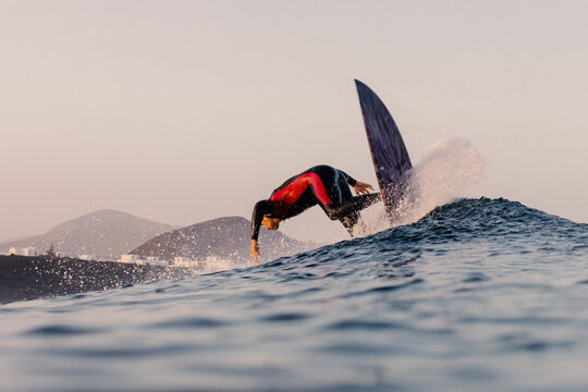 Skilled surfer performing a reentry on the peak of a towering wave