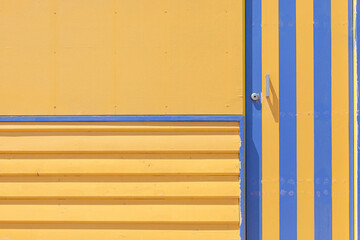 Yellow beach hut with contrasting blue stripes and latch