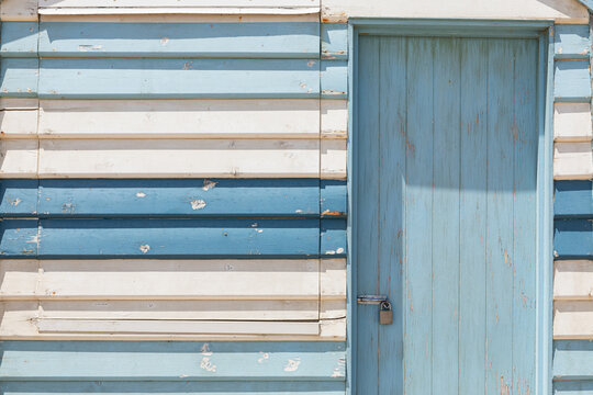 Weathered blue and white beach shack with locked door