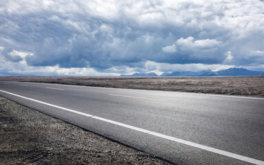 Fototapeta premium Asphalt road and desert natural landscape under cloudy sky
