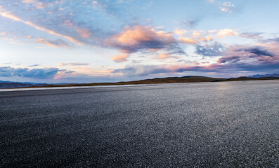 Asphalt road and mountains with colorful sky clouds at sunset