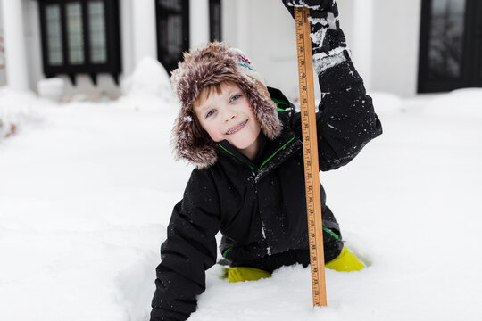 boy holds a measuring stick in the snow