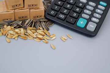 Sunflower seeds, calculator and cardboard boxes on gray background. Copy space for text.