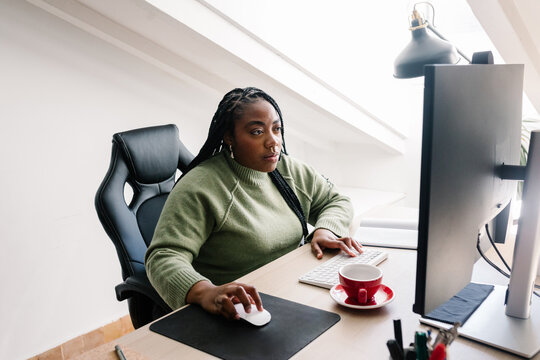 Female focused young freelancer carefully reviews a creative project