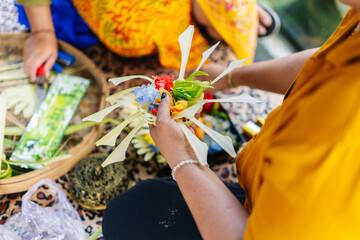 Balinese women preparing Canang sari with colorful flowers and leaves